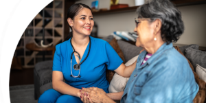 A woman receiving nursing care at home in Saginaw holds the hand of her nurse and smiles.