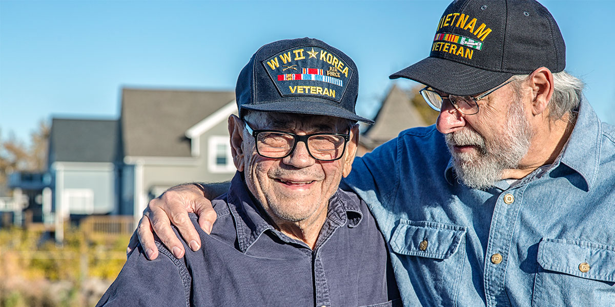 An older man wraps an arm around his buddy, both veterans receiving veterans’ care in the Saginaw area.