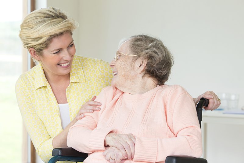 An older woman smiles from her wheelchair at her geriatric care manager.