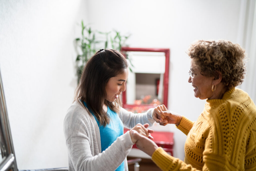 A caregiver who knows what it’s like when you’re living with multiple sclerosis helps an older woman with mobility challenges.